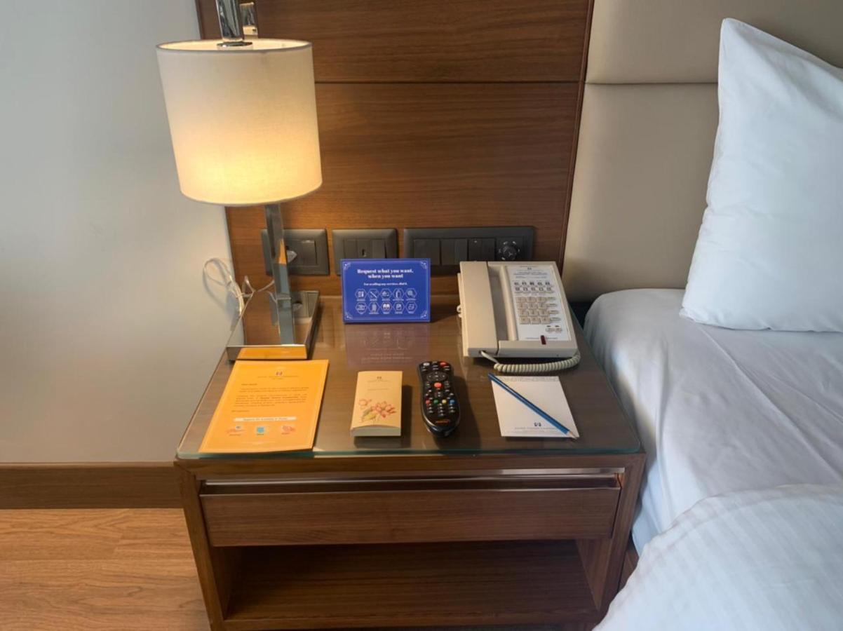 Jaypee Vasant Continental Hotel Új-Delhi Kültér fotó A bedside table with a telephone, a lamp, a pen and a notepad